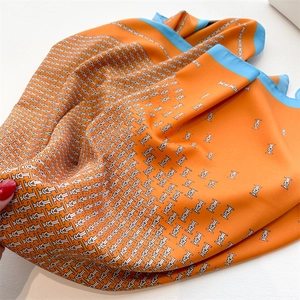 Orange silk square scarf with blue borders and equestrian pattern on white backdrop