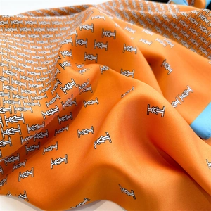 Detail of orange twill silk scarf with blue hand-rolled edges and knot pattern