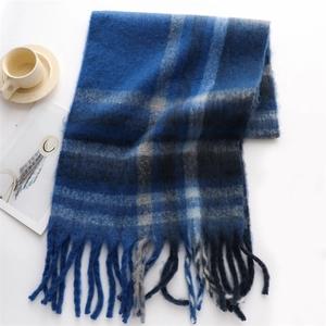 Flat lay of blue plaid cashmere scarf with long tassels next to a coffee cup