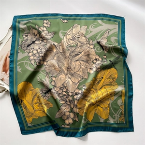 Detailed close-up of a square silk scarf with floral, butterfly, and dragonfly patterns