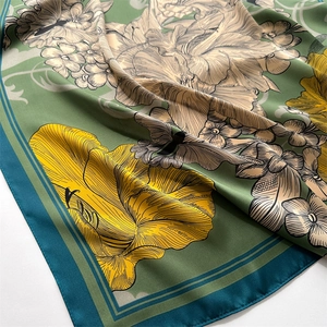 Detail of olive green silk scarf featuring yellow peony floral prints and satin texture