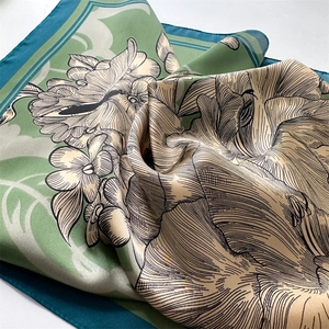 Close-up of silk texture scarf with elegant green peony floral print and satin finish