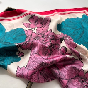 Detailed view of peony floral print on silky satin scarf with elegant red border trim