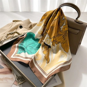 Detail of silk scarf with peony flowers and butterfly draped over a brown leather bag