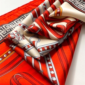 Detail eines Seidenschals mit Reitmuster und Mäander-Design in Orange und Beige
