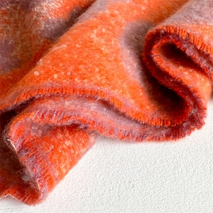 Nahaufnahme des dicken orange-grauen Strickschals mit weichem Mohair-Effekt und Fransen