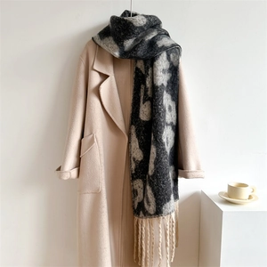Detailansicht des Jacquard-Schals mit Leopardenmuster und beigen Fransen am Wollmantel