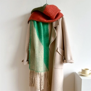 Écharpe épaisse à blocs de couleurs orange, vert et beige drapée sur un manteau