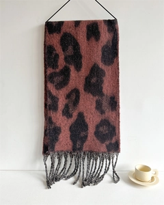 Detail eines klobigen Leoparden-Strickschals mit rotbraunem Muster und grauen Quasten