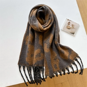 Detailansicht eines dicken Schals mit Blumenmuster, schwarzen Fransen und Strickstruktur
