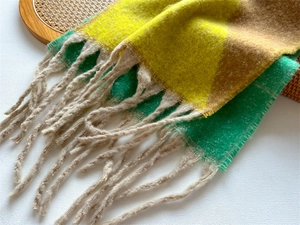 Gros plan d'une écharpe à franges multicolore en faux cachemire doux jaune, vert et marron