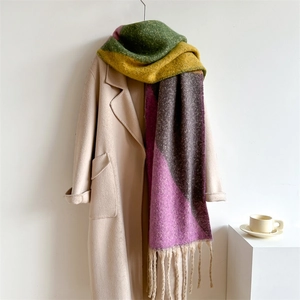 Détail d'une écharpe en tricot colorée à franges sur un manteau d'hiver beige