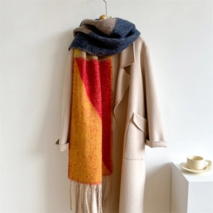 Détail de l'écharpe en maille épaisse avec blocs orange et bleus et glands à franges