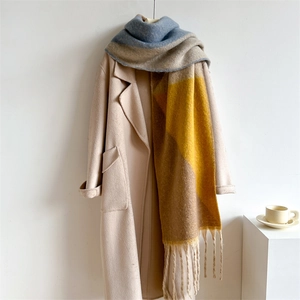 Détail d'une écharpe épaisse en blocs de couleurs avec franges et manteau beige