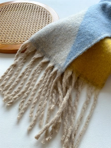 Détail d'écharpe épaisse avec blocs beige bleu jaune et longues franges torsadées