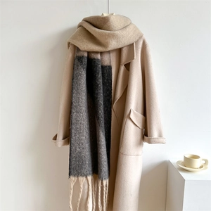 Détail d'une écharpe à franges multicolore avec un manteau en laine beige au style épuré