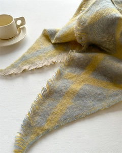 Détail d'une écharpe à carreaux jaune et gris en fil bouclé avec des bords à franges