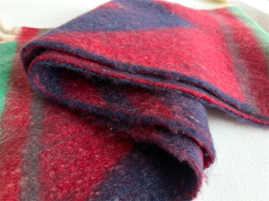Close-up of thick boucle wool scarf showing textured red, blue, and green plaid weave