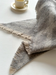 Détail de l'écharpe en fil bouclé gris et crème avec des franges et une texture douce