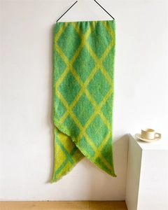 Gros plan sur une longue écharpe à carreaux verts et jaunes avec franges et texture douce