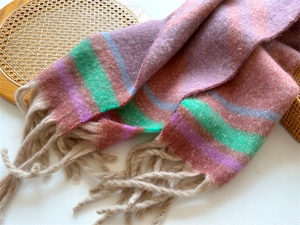 Close-up of thick striped winter scarf with soft faux cashmere texture and long tassels