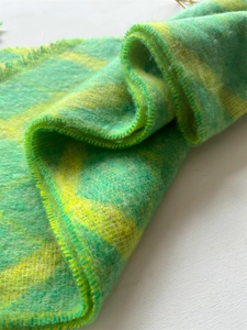Vue détaillée d'une écharpe en peluche épaisse avec motif à carreaux vert et jaune et ourlet