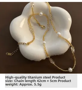 Détail d'un collier en perles et acier titane doré sur un plateau floral en céramique