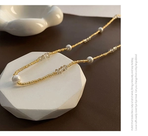 Détail d'un collier de perles style français avec perles dorées et accents facettés