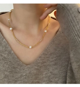 Détail d'un collier de perles dorées de style français avec perles blanches élégantes