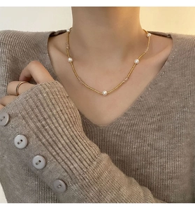 Gros plan détaillé d'un collier de perles dorées porté par un mannequin en pull en maille