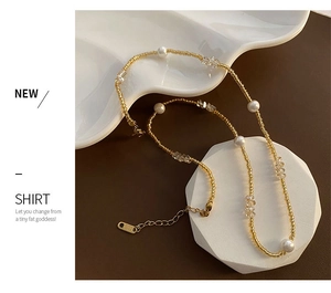 Détail d'un collier de perles élégant avec billes dorées et cristaux sur support blanc