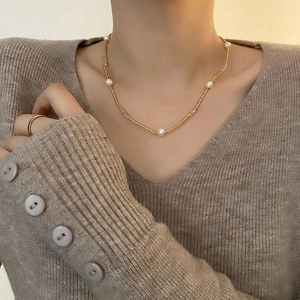 Collier de perles de style français élégant avec perles dorées sur un mannequin en gilet gris