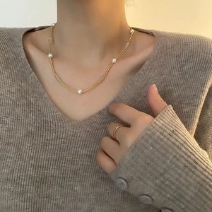Collier minimaliste en chaîne dorée avec perles et perles porté avec bague assortie