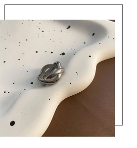 Detailed close-up of a silver knot ring on a white ceramic tray with soft lighting