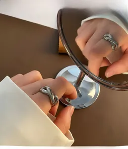 Mirror reflection showing a polished silver infinity knot ring on a model's finger