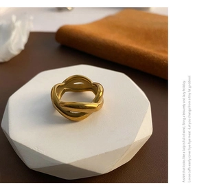 Detail of an 18K gold plated twisted ring displayed on a geometric stone pedestal