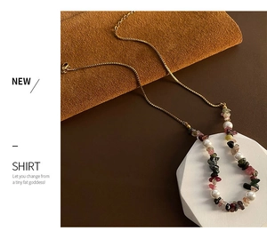 Detail of beaded necklace featuring colorful stones, white pearls and golden box chain