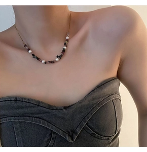 Close-up of agate stone and pearl necklace worn by a model in casual grey top