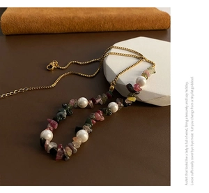 Detail view of colorful gravel stones and pearls on a gold-plated necklace chain