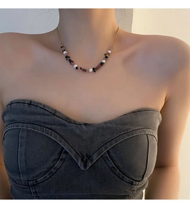 Detail of colorful crushed stone and pearl necklace worn by a model on collarbone