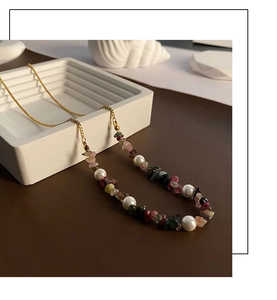 Detail of colorful agate gravel and pearl pendant necklace on a decorative tray