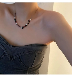 Close-up of pearl and black agate stone necklace worn on a female model neck