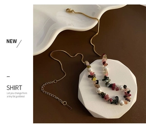 Detail of gold necklace with colorful irregular crushed stones and elegant pearls