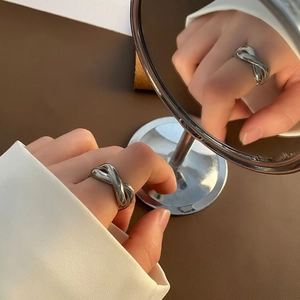 Polished silver knot ring in twisted metal design worn on index finger for women