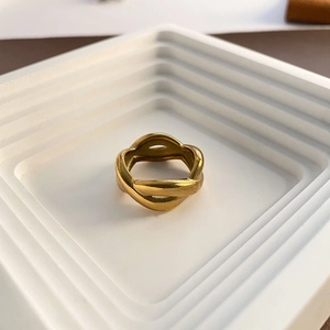 Minimalist 18K gold plated twisted metal ring displayed on a white marble pedestal