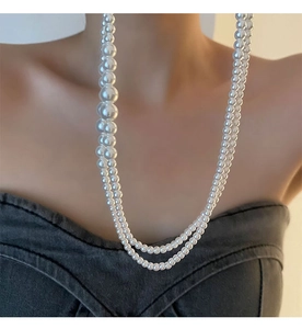 Gros plan d'un collier de perles à double rangée avec dégradé de perles blanches