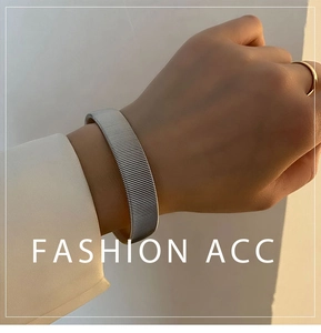 Detail of silver titanium steel elastic bracelet with textured band on female wrist