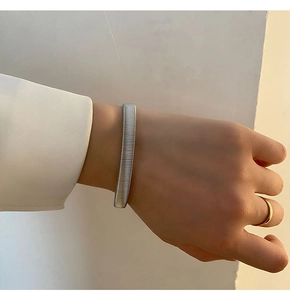 Detail of a minimalist silver twisted cuff bracelet worn with a white blazer outfit