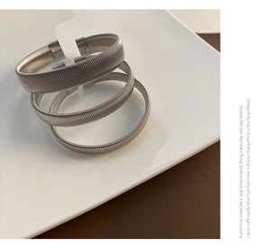 Detailed view of three silver titanium steel elastic spiral spring bracelets on white ceramic