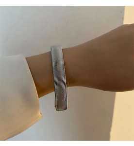 Close-up of the woven metal texture and silver stainless steel band of the adjustable bracelet